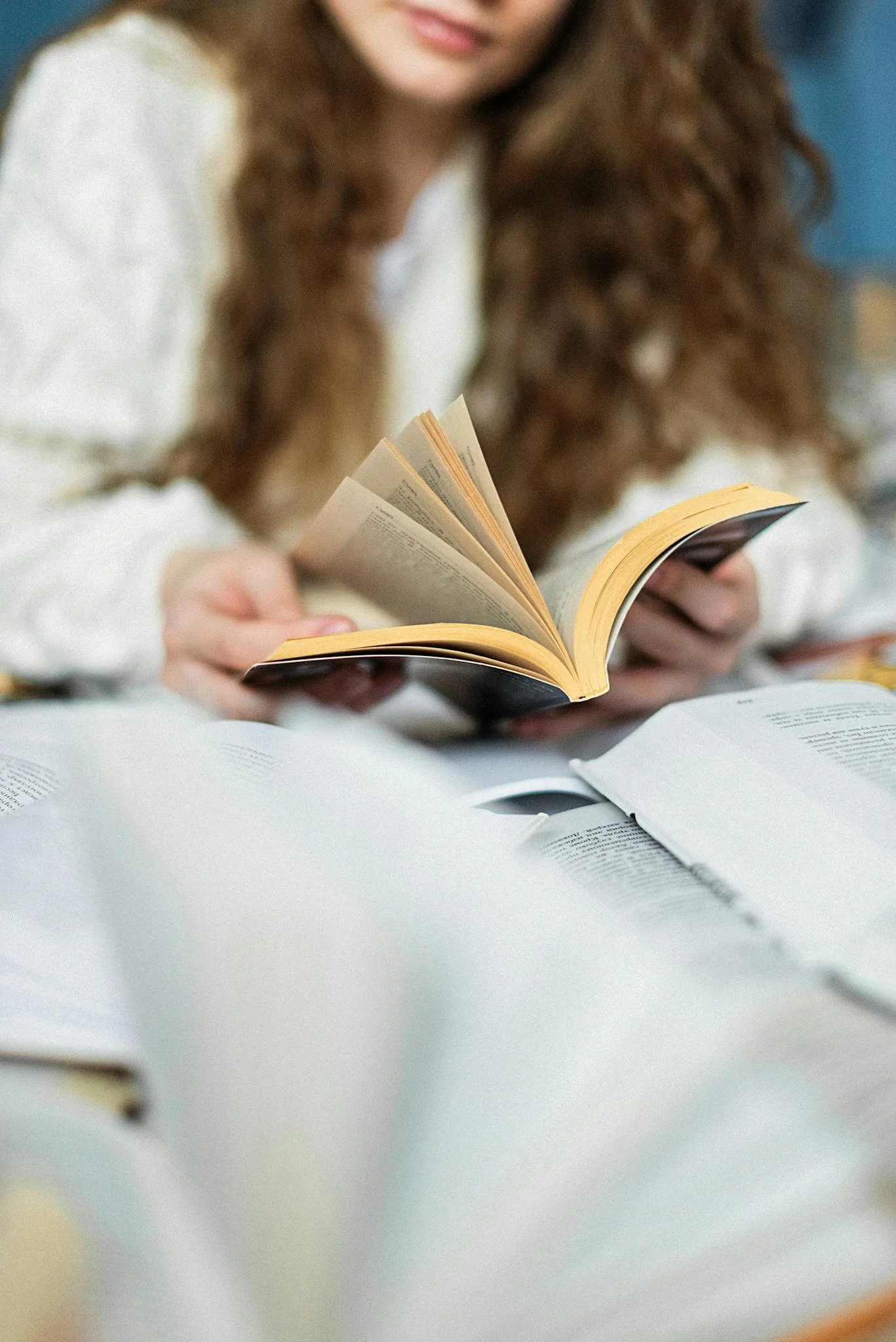 A person immersed in reading, surrounded by open books, creating a peaceful atmosphere.